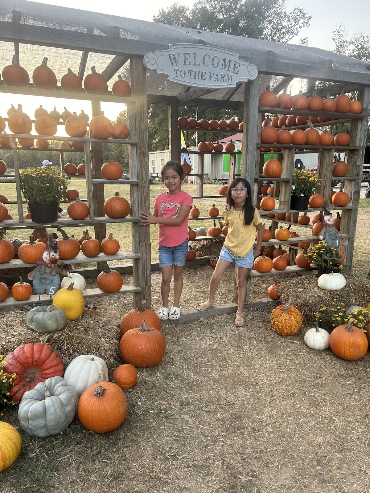 Two girls in front of shelves stacked with pumpkins and gourds
