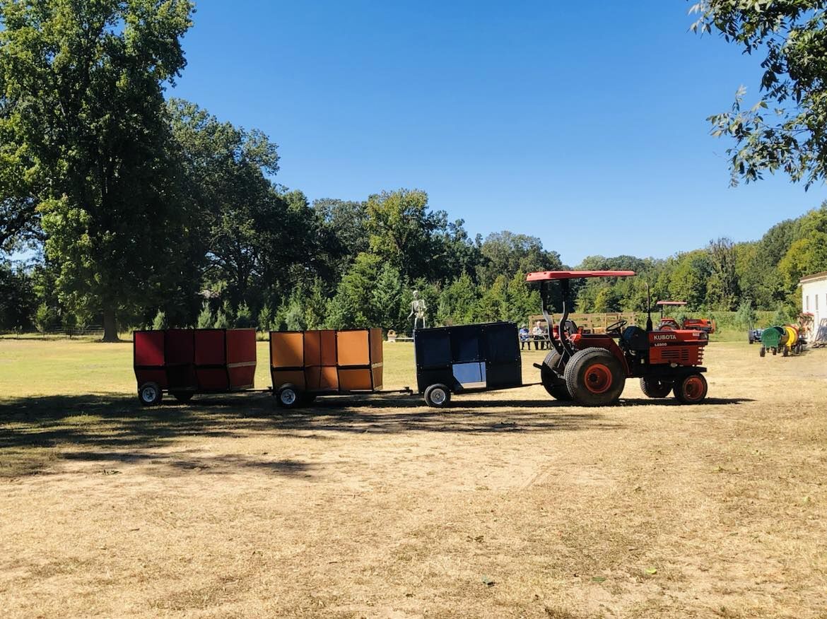 A tractor with the barrel train cars under a blue sky