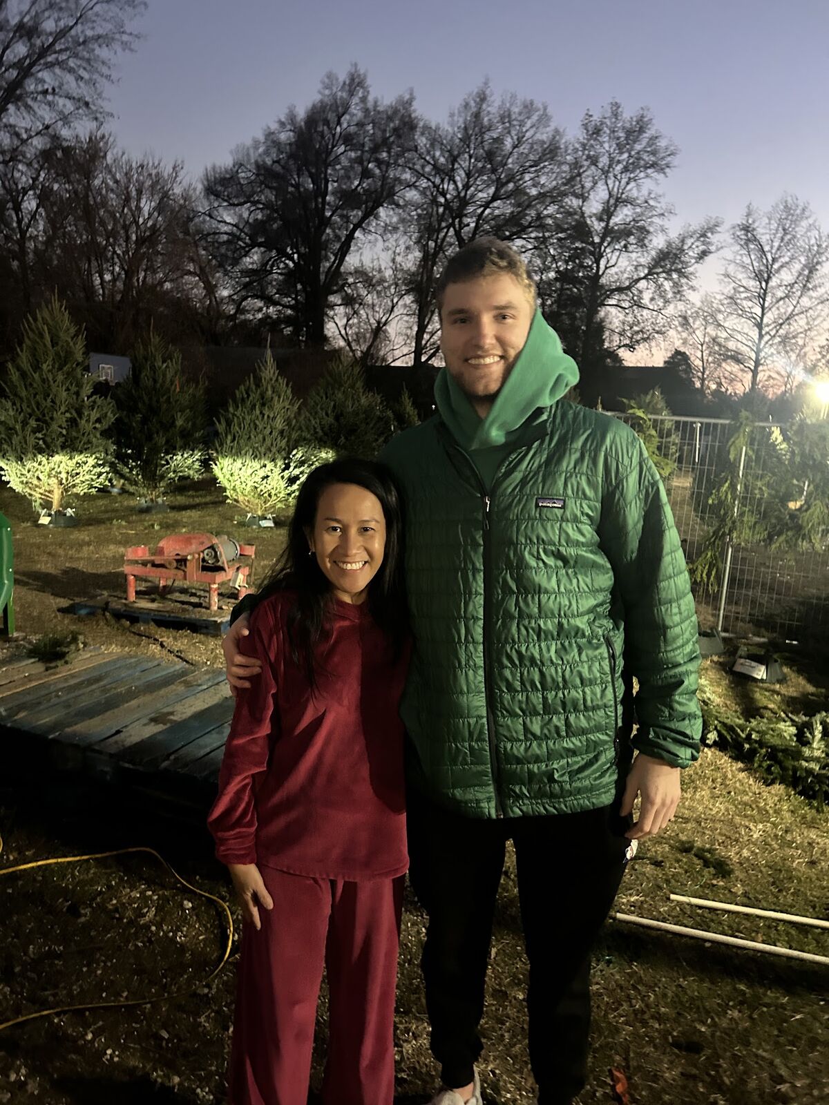 Two visitors smiling in the Christmas tree lot