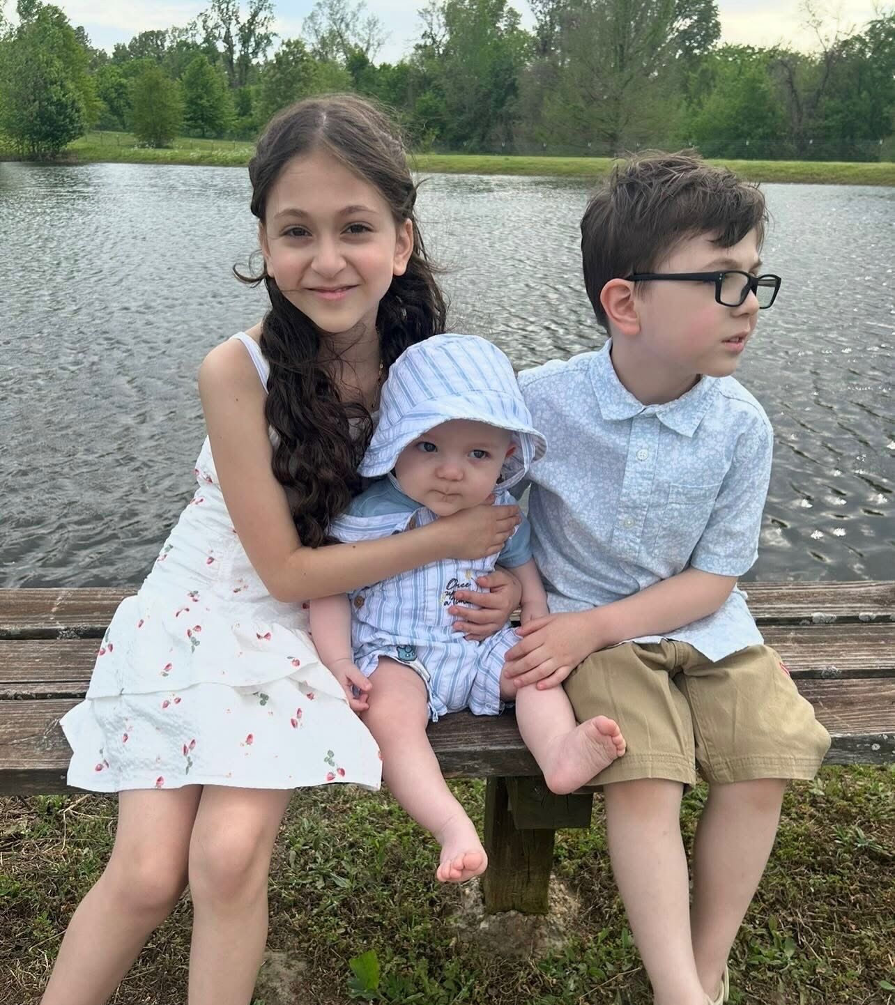 Three children sitting together by the lake